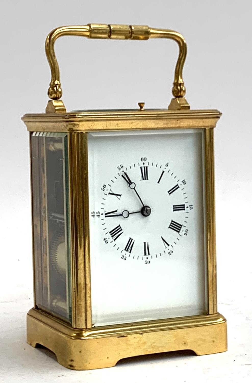 A heavy gilt metal carriage clock, bevelled glass panels, enamel dial with Roman numerals,