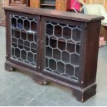 An early 20th century lead glazed bookcase, moulded top over two doors, on bracket feet,