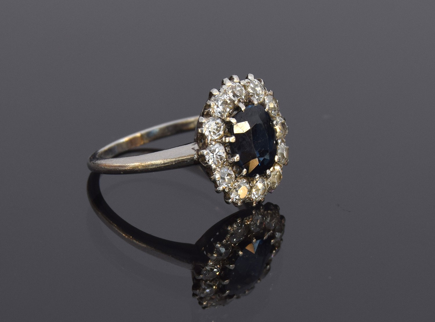 An early 20th century platinum, sapphire and diamond cluster ring, the central mixed cut sapphire