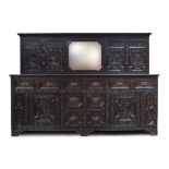 A very substantial late Victorian oak sideboard, the upstand with central mirror, the whole carved