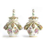 A pair of floral encrusted lidded urns, hand painted with encrusted swags, each lid with