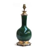 A ceramic table lamp of bottle form glazed in emerald green, mounted in white metal, incised with