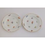 A pair of early 20th century Meissen side plates, with hand painted floral decoration, heightened in