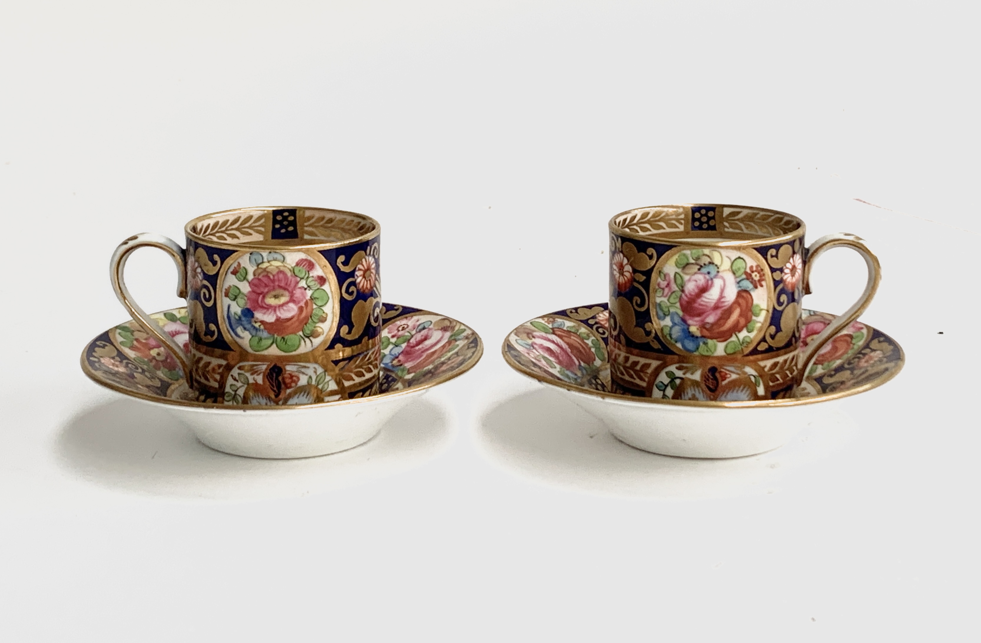 A pair of 19th century Crown Staffordshire coffee cups and saucers, hand painted with floral decorat