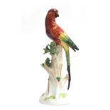 A 20th century Dresden porcelain model of a parrot perched upon a tree stump, marked to base with