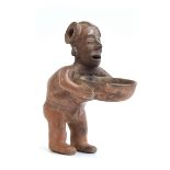 A Pre-Colombian pottery figural vessel in the form of a man holding a dish, 27cm high Provenance: