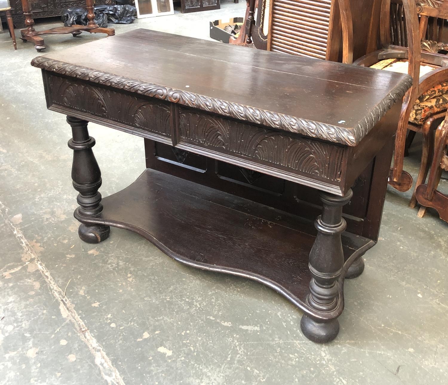 A Victorian side table with two frieze drawers with carved fronts, on baluster supports, on