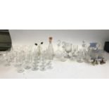 A mixed lot of plain and etched glass port and sherry glasses, together with various decanters and