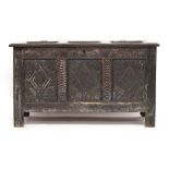 A 17th/18th century three panel oak coffer, carved with demilune frieze over three lozenge carved