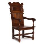 An 18th century oak wainscot chair, shaped cresting rail, over a panelled back, turned uprights