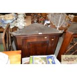 An antique oak hanging corner cupboard