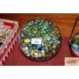 A glass bowl containing various marbles