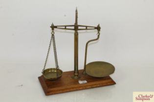 A set of brass balance scales on wooden plinth