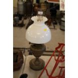 A brass oil lamp with opaque glass shade