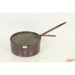An antique copper saucepan and lid with cast iron