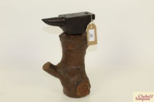 A small bench type anvil mounted to a wooden tree