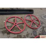 A pair of red painted heavy iron wheels