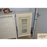 A modern cream painted cabinet with pierced and gl