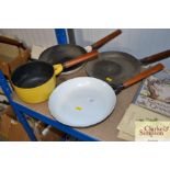 A cast iron and enamel saucepan and three frying p