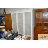 A painted triple wardrobe with wire mesh doors