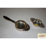 A silver tea strainer and one other