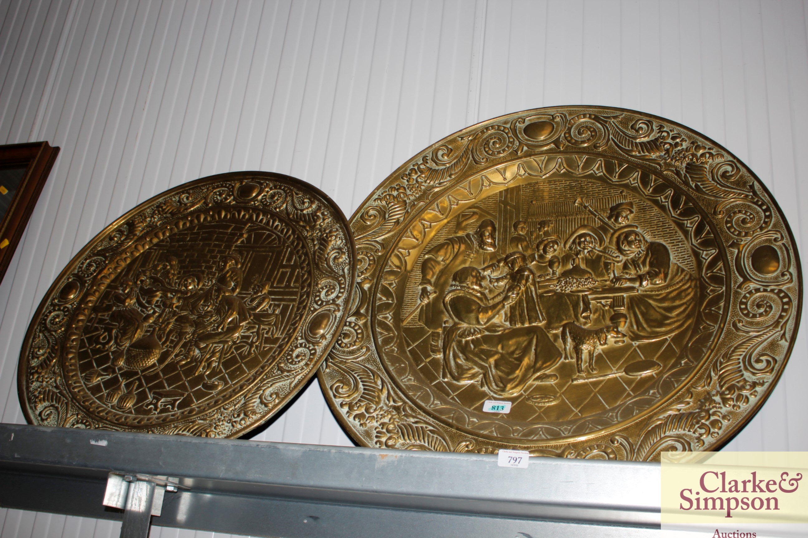 Two circular brass embossed plaques depicting tavern scenes