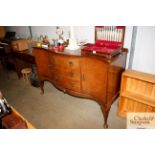 A walnut serpentine fronted sideboard raised on ca