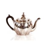A George III silver teapot, of oval fluted form having foliate engraved decoration surmounted by a