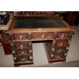 A late Victorian carved oak pedestal writing desk, the leatherette inset top above three frieze