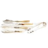 Three mother of pearl handled butter knives, and a pair of Victorian silver sugar tongs, London 1844