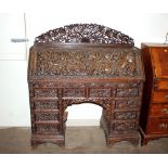 A carved hardwood Burmese bureau, profusely decorated with foliage, the fall front opening to reveal