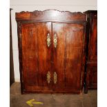 An 18th Century fruit wood armoire, the interior enclosed by a pair of panelled doors with brass