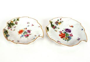 A pair of Meissen leaf shaped dishes, having painted and floral encrusted decoration, heightened