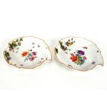 A pair of Meissen leaf shaped dishes, having painted and floral encrusted decoration, heightened