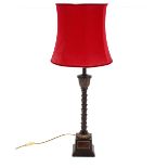 A bronze effect table lamp, with leaf decoration raised on square plinth complete with red shade,