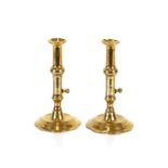 A pair of antique brass ejector candlesticks, raised on petal bases, 19cm high