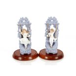 A pair of blue bisque ware hollow figures, of a boy and girl on swings under later glass domes