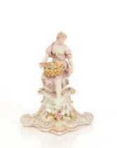 A Dresden style porcelain figure, of a maiden with basket of flowers seated on a plinth, 29cm high