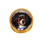 A Victorian yellow metal and enamel circular brooch, inset with a study of a King Charles Spaniel,