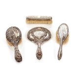 A late Victorian silver backed hand mirror, Birmingham 1894; two silver backed hair brushes; and a