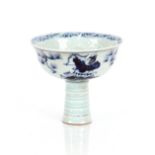 An Oriental blue and white stem cup, decorated figures and flowers with relief dragon interior, 11cm