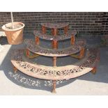 A Victorian cast iron four tier graduated plant stand, of demi-lune shape, having pierced foliate