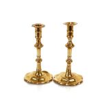 A pair of antique brass ejector candlesticks, raised on turned columns with petal bases, 20cm high