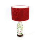 An Oriental porcelain baluster table lamp, having foliate decoration complete with red silk shade,