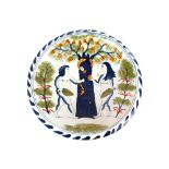A Bristol Delftware "Adam and Eve" decorated charger, painted in dark blue and green, serpent and