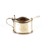 A late Victorian silver mustard pot, engraved with a family crest, domed lid and fluted thumb piece,
