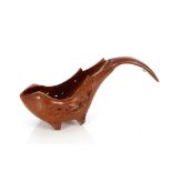 A carved hardwood pouring scoop, in the form of a whale with leaf decorated sides on four feet,