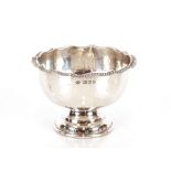 A George V silver pedestal bowl, having spot hammered decoration beneath a shaped gadrooned