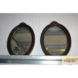 A pair of black painted oval wall mirrors
