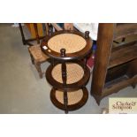 A three tier mahogany and cane side stand